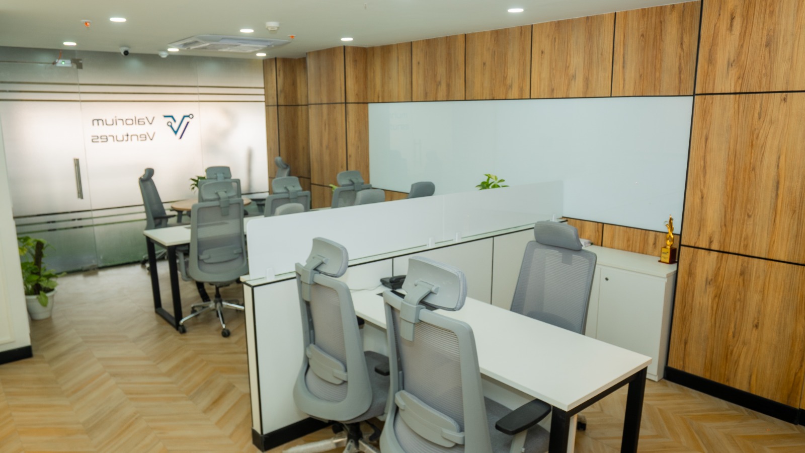 Collaborative workstation bay with shared desk and muted finishes at Valorium Ventures office interior